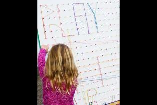 Child playing with strong on board with PLAY spelled out