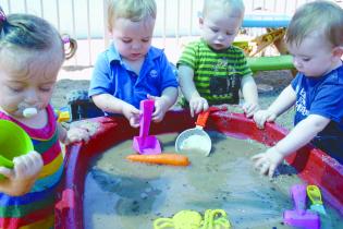 Toddlers playing in a water and sand tray