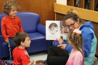 Student reading to three children in a circle