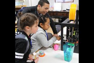Teacher showing 3D printer to students