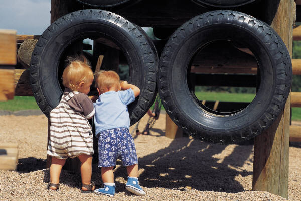 Two Toddlers looking into hanging tires