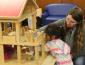 Student playing in doll house with child