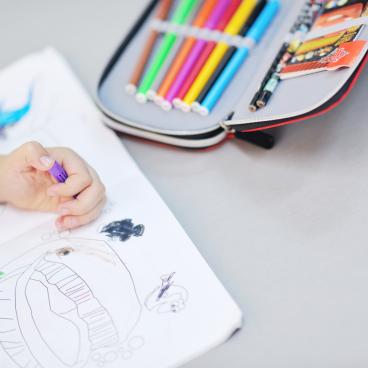 Child drawing in coloring book with markers