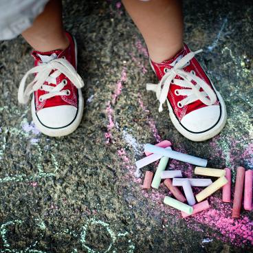 Child in red sneakers standing above chalk
